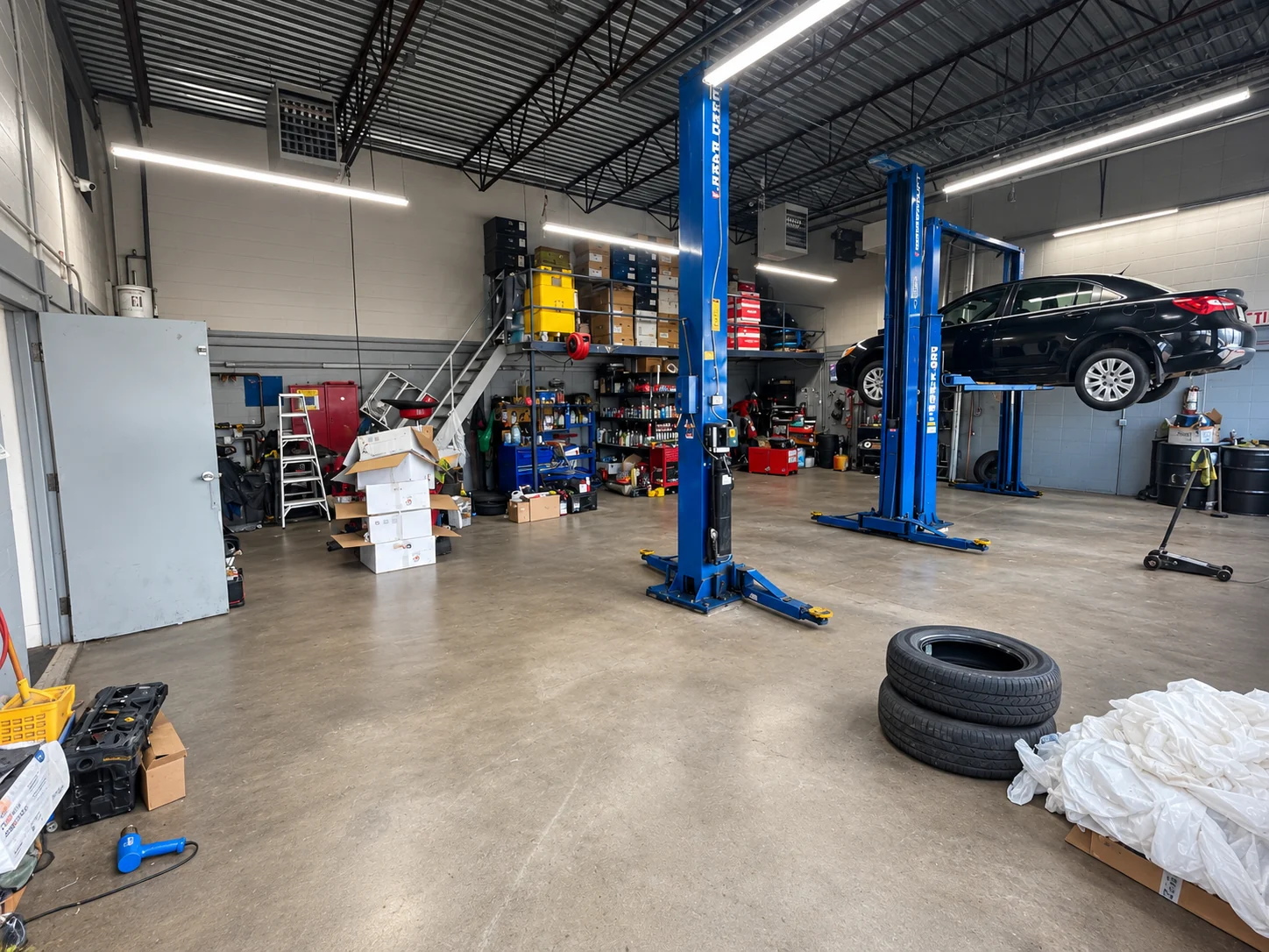 Workshop with a sedan raised on a lift and tool storage